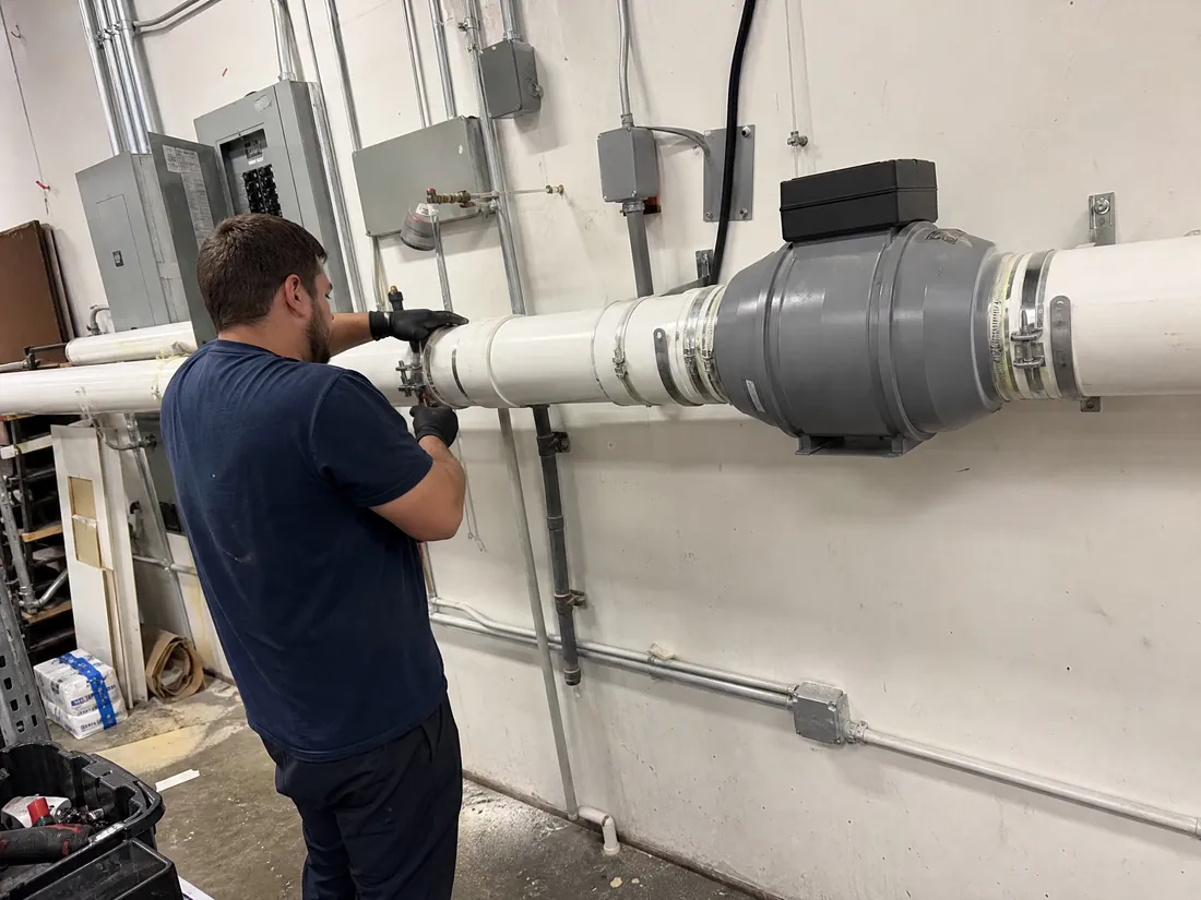 Technician installing a commercial radon mitigation riser in a Los Angeles building mechanical room